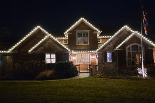 House with white Christmas lights outlining the roofline at night.