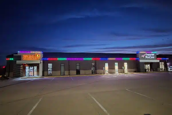 Building with holiday lights above storefronts for 3CT Bluff Pharmacy and Beyond Hill Eye Care.